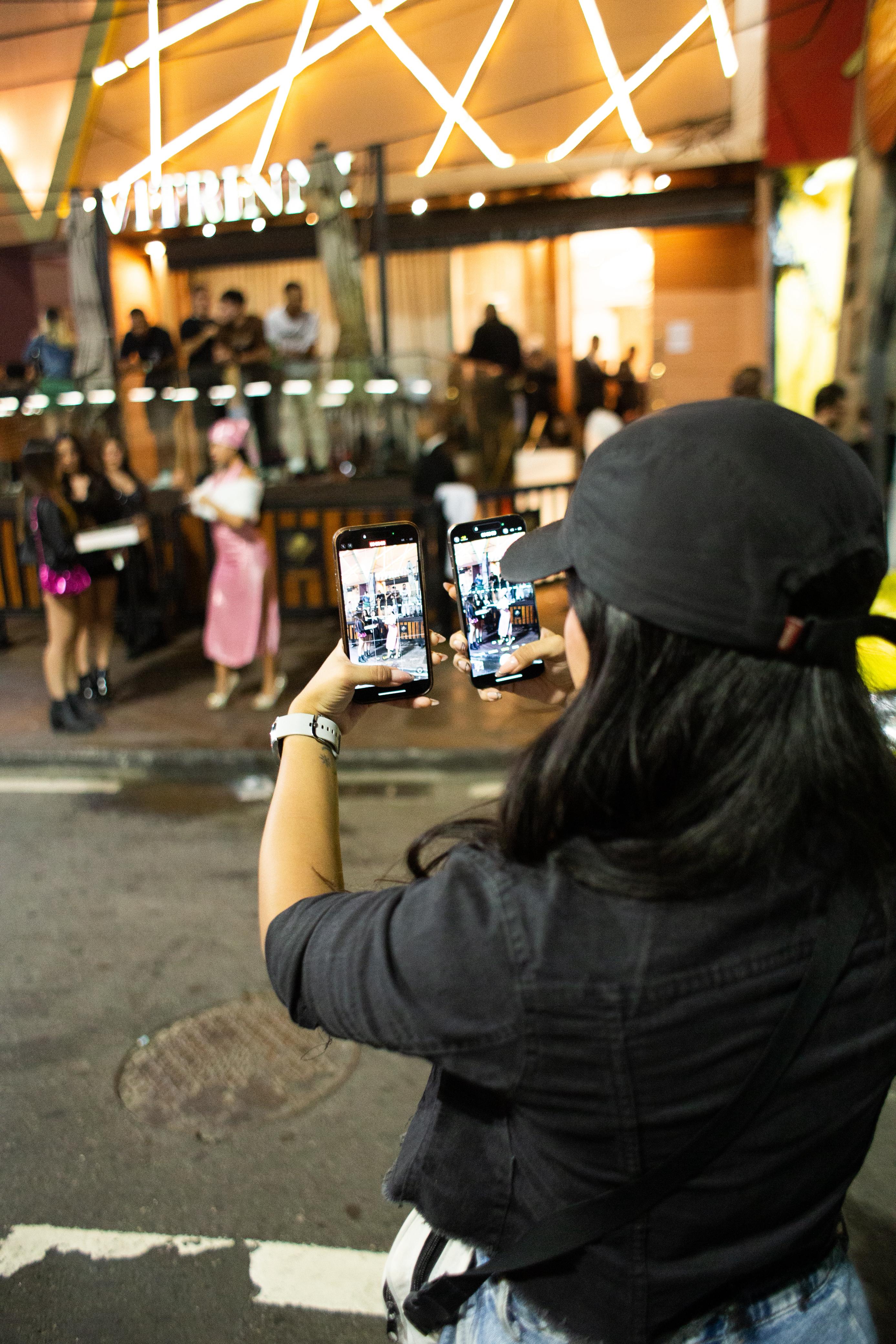 Bea Jones capturando conteúdo em shopping center com dois smartphones
